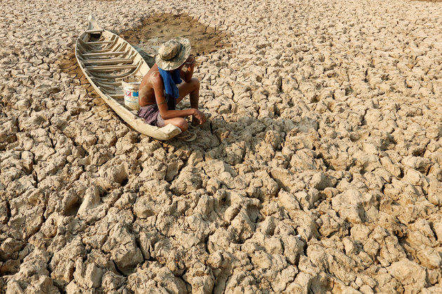A fisherman sits to smoke on his boat at a Bak Angrout dried up pond at the drought-hit Kandal province in Cambodia