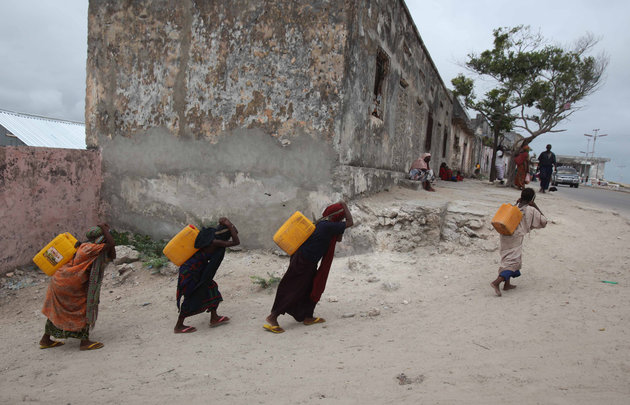 Internally displaced women carry jerry-cans of water on their backs from a well in Somalia's capital Mogadishu