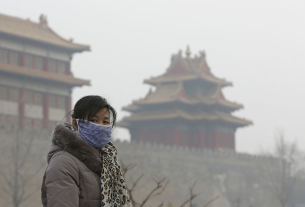 A visitor wearing a mask walks outside the Forbidden City in central Beijing